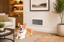 Load image into Gallery viewer, Flo-Matrix single deflection vertical blade supply air grille installed in a warm modern living room, featuring adjustable side-to-side airflow control and a clean architectural finish for residential HVAC systems.
